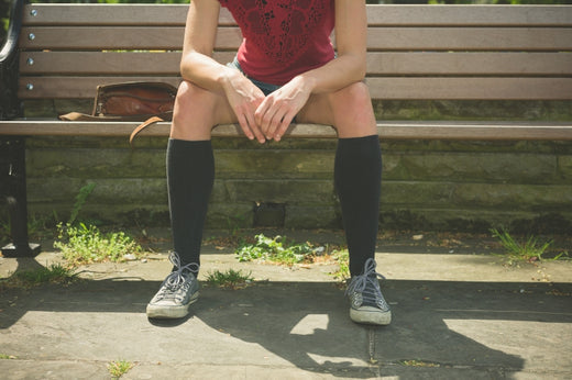 A person wearing hywell black knee-high socks is sitting on a chair and resting