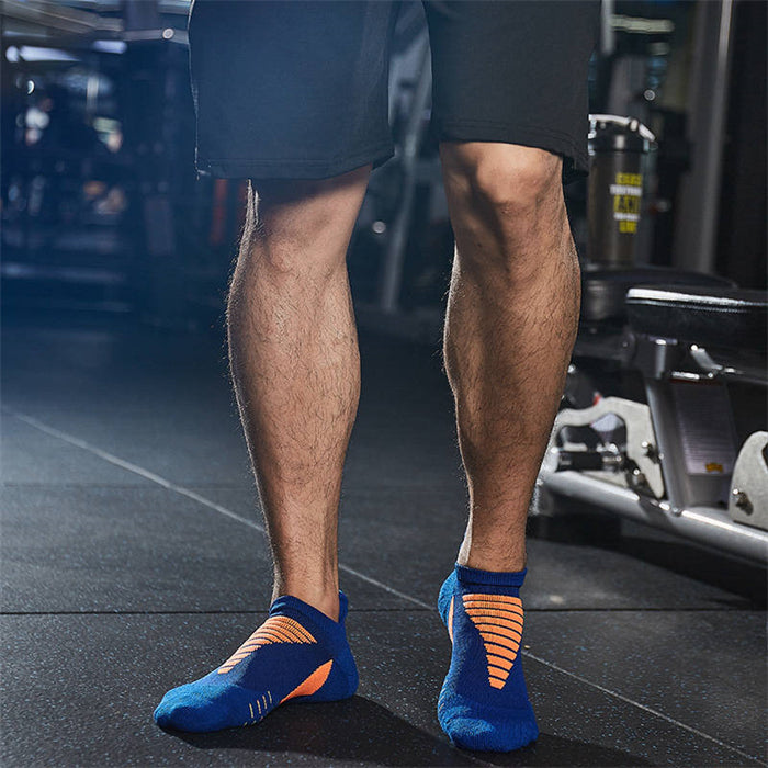 Man wearing blue and orange athletic ankle socks with arch support design in a gym setting