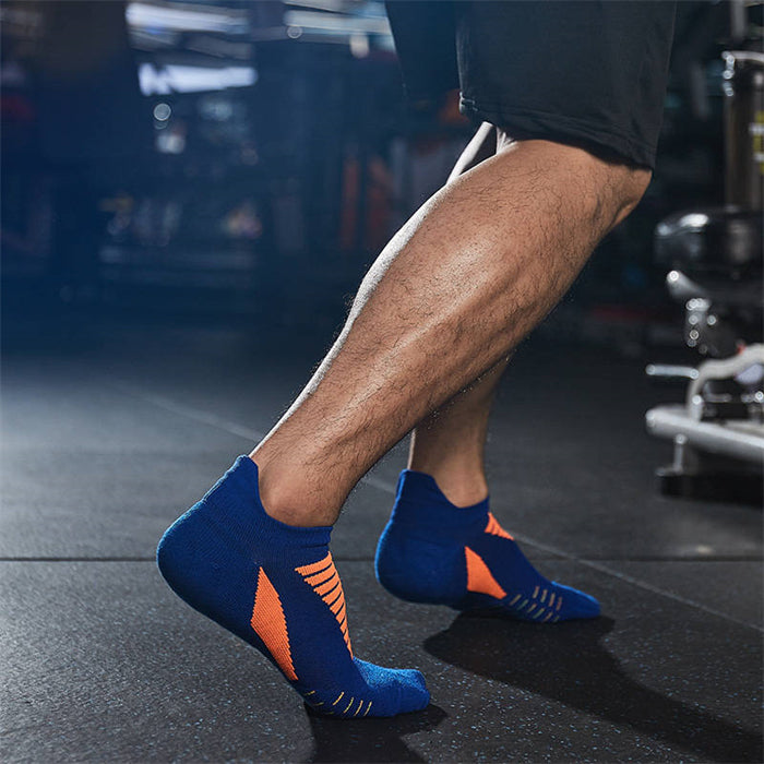 Man wearing blue and orange athletic ankle socks with arch support design in a gym setting