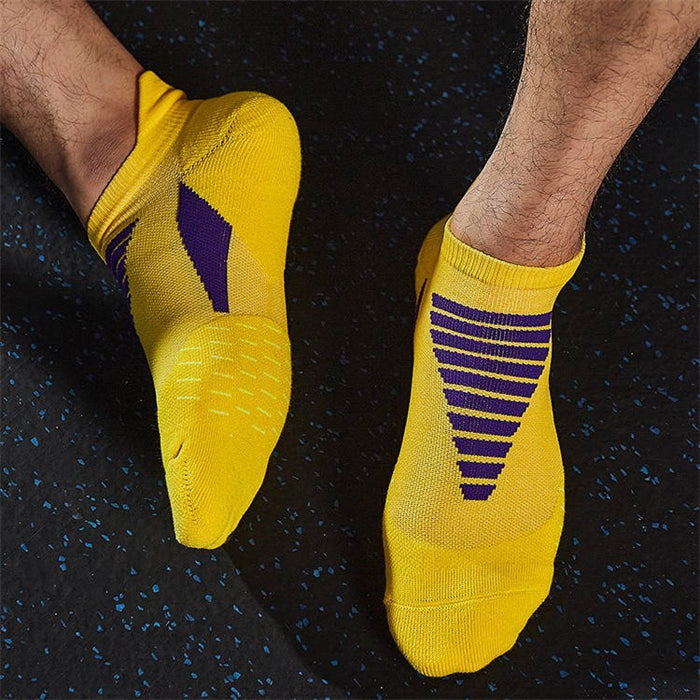 Person standing in yellow athletic socks with purple accents and anti-slip grip on the sole, on a speckled gym floor