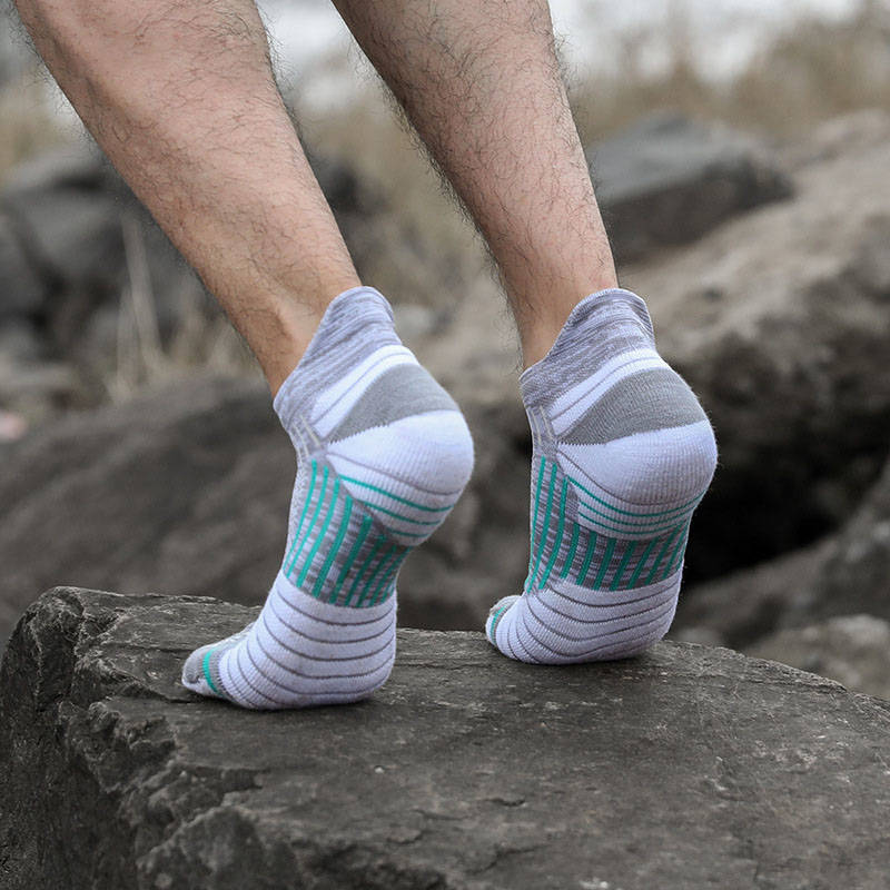 Man wearing compression running socks on rocky terrain, offering support and grip for outdoor activities.