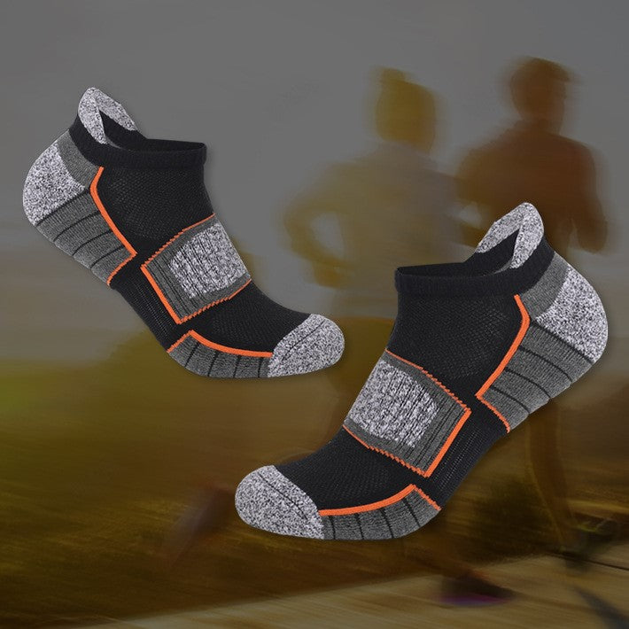 "Black and gray ankle socks with orange accents, displayed with a blurred background of running figures.