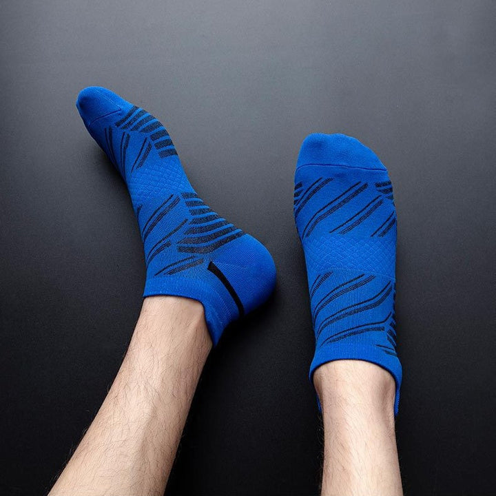 Person wearing blue ankle socks with black dynamic stripes on a dark background.