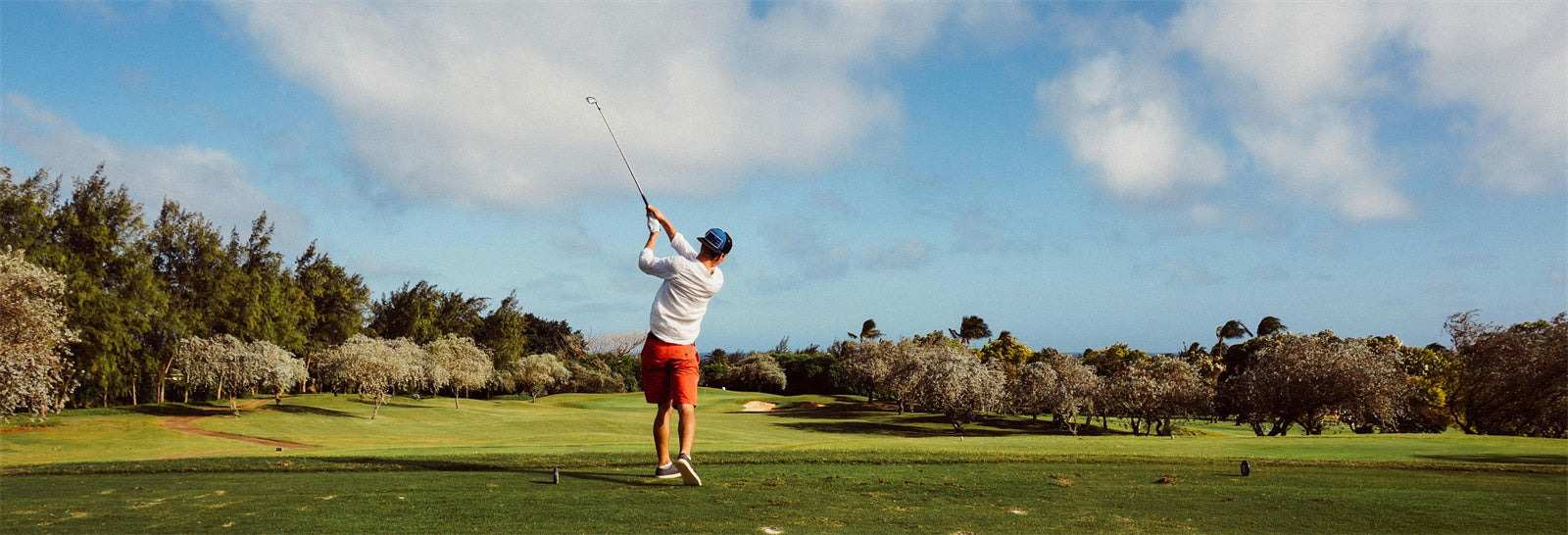 Golfer swinging on a sunny golf course