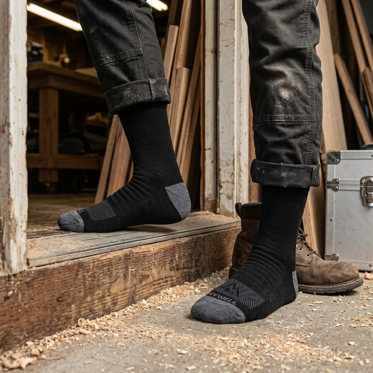 Worker wearing black Merino wool work socks in a workshop doorway