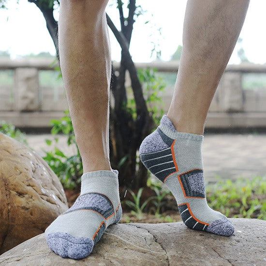Man wearing light gray ankle socks with dark gray and orange accents outdoors.
