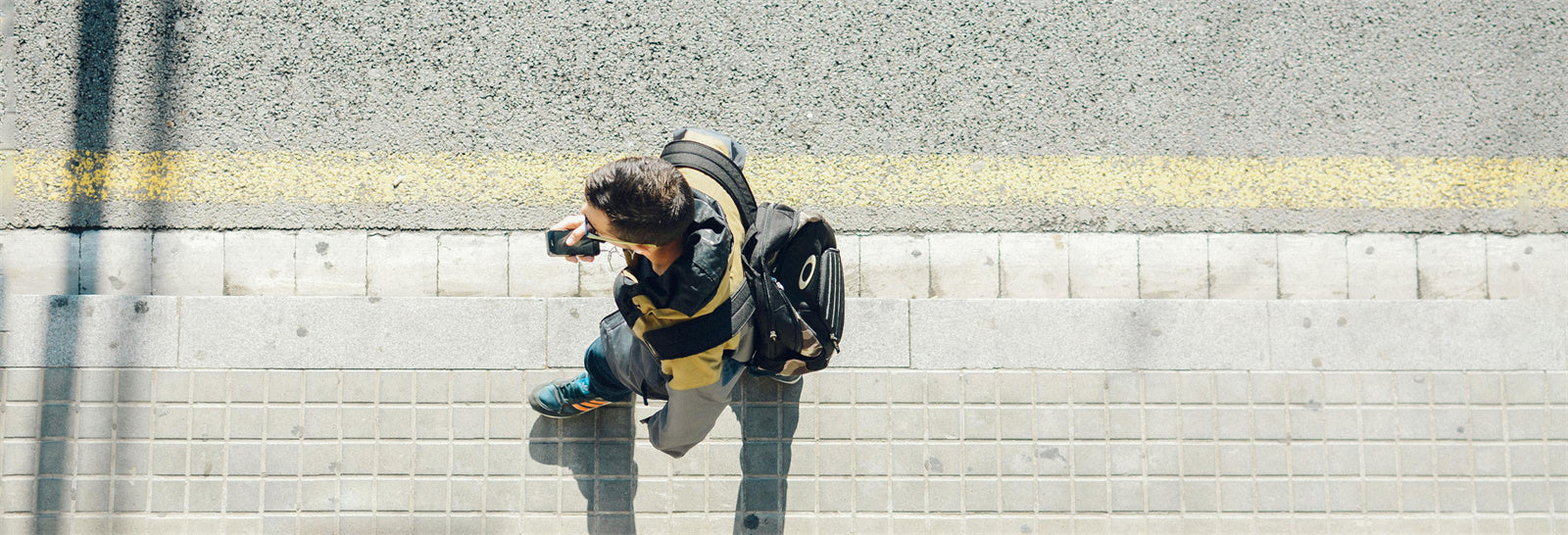 Person walking on a sidewalk with a backpack.